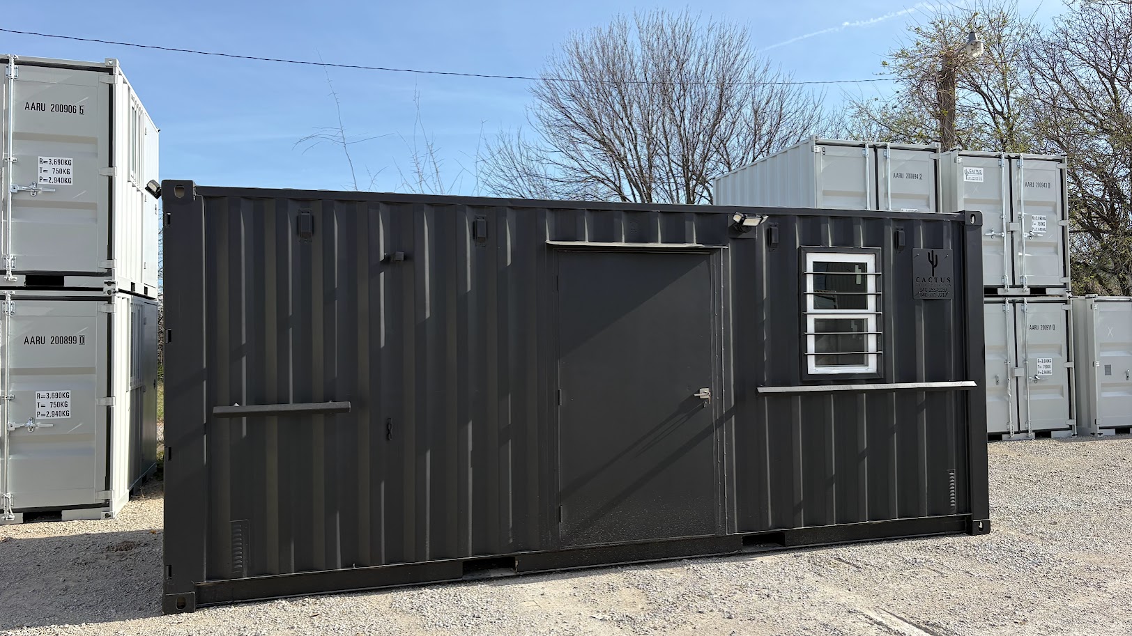 Two black container office conversions built by Cactus Containers, with windows, security bars and steel entry doors, at a Texas yard